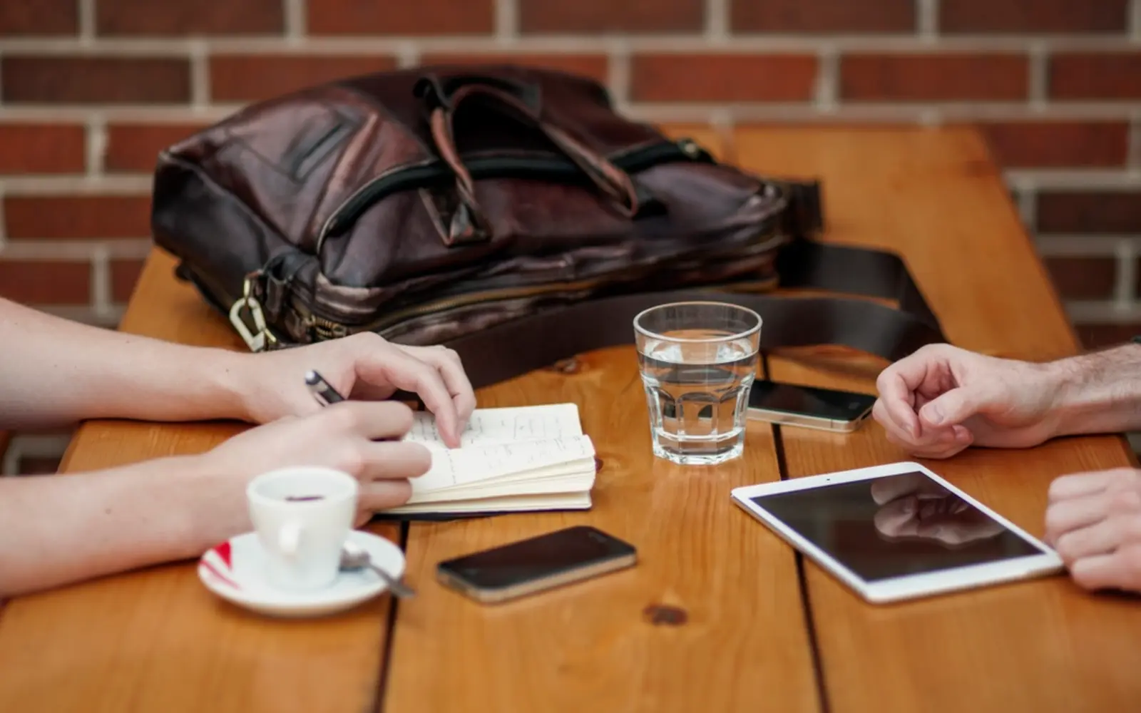 Two people meeting over coffee with a notebook