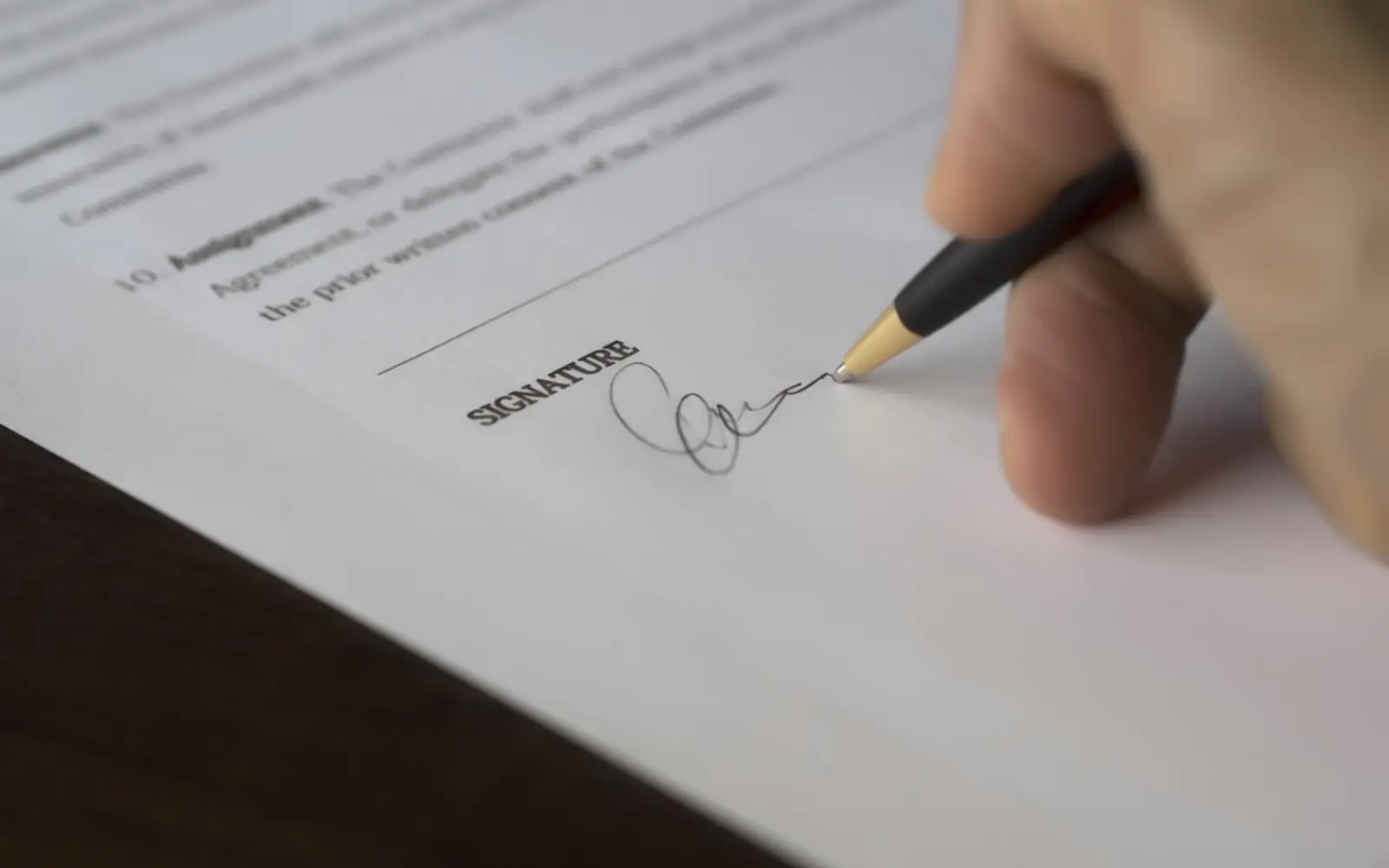 A hand signing a document with a pen